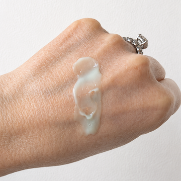 Hand with a small amount of cream on a plain background